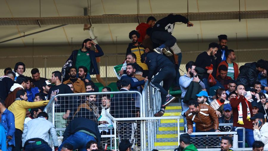 Anggota tim keamanan stadion Irak membawa seorang penggemar sepak bola yang terluka ke area darurat di Stadion Internasional Basra menyusul penyerbuan menjelang pertandingan final Piala Teluk Arab malam ini antara Irak dan Oman, pada 19 Januari 2023 di Basra. - Satu orang tewas dan puluhan lainnya terluka ketika terjadi penyerbuan di luar stadion sepak bola di Irak selatan beberapa jam sebelum final Piala Teluk, kata sumber medis dan keamanan. (HUSSEIN FALEH/AFP via Getty Images)