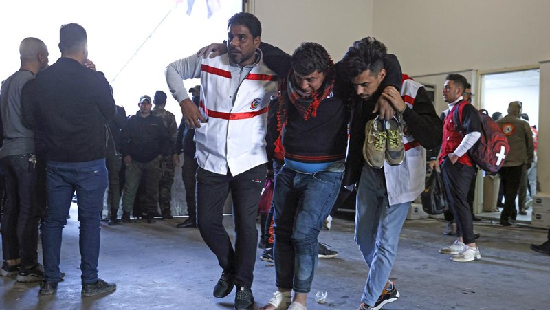 Anggota tim keamanan stadion Irak membawa seorang penggemar sepak bola yang terluka ke area darurat di Stadion Internasional Basra menyusul penyerbuan menjelang pertandingan final Piala Teluk Arab malam ini antara Irak dan Oman, pada 19 Januari 2023 di Basra. - Satu orang tewas dan puluhan lainnya terluka ketika terjadi penyerbuan di luar stadion sepak bola di Irak selatan beberapa jam sebelum final Piala Teluk, kata sumber medis dan keamanan. (HUSSEIN FALEH/AFP via Getty Images)