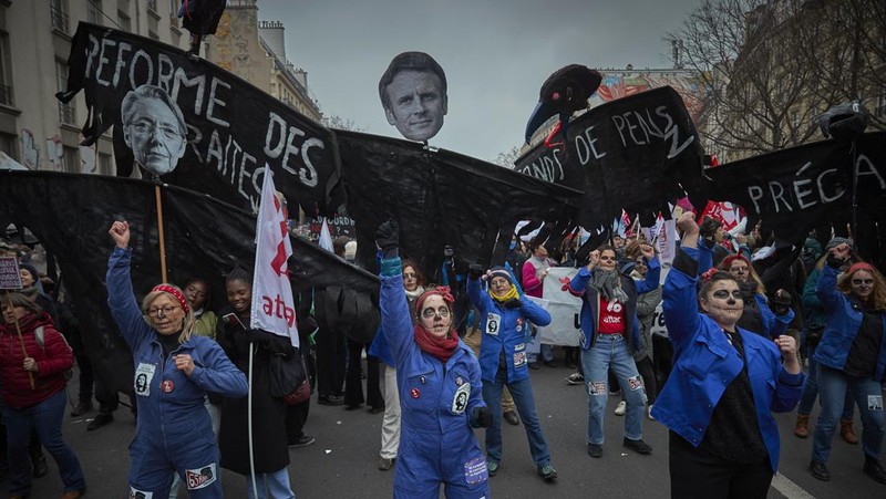 Para pengunjuk rasa berbaris melalui jalan-jalan Paris sebagai bagian dari protes dan pemogokan nasional terhadap rencana reformasi Pensiun Presiden Macron dan kenaikan biaya hidup pada 19 Januari 2023 di Paris, Prancis. Menyusul pengumuman pemerintah Prancis untuk mendorong usia pensiun dari 62 menjadi 64, serikat pekerja menyerukan aksi sosial massal dengan karyawan di bidang transportasi, pendidikan, energi, dan layanan kesehatan bergabung dengan pemogokan nasional, dengan protes besar di seluruh Prancis. Serikat CGT Prancis juga mengancam akan memutus pasokan listrik untuk anggota parlemen dan pengusaha di tengah pemogokan nasional. (Kiran Ridley/Getty Images)