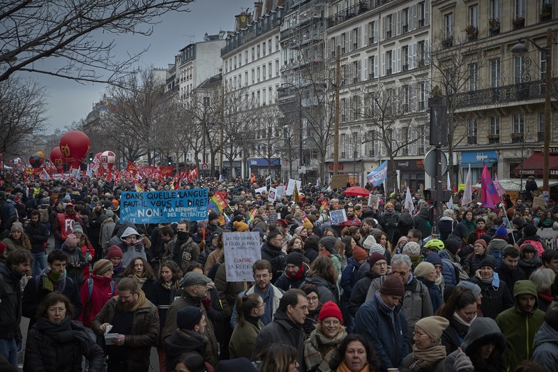 Para pengunjuk rasa berbaris melalui jalan-jalan Paris sebagai bagian dari protes dan pemogokan nasional terhadap rencana reformasi Pensiun Presiden Macron dan kenaikan biaya hidup pada 19 Januari 2023 di Paris, Prancis. Menyusul pengumuman pemerintah Prancis untuk mendorong usia pensiun dari 62 menjadi 64, serikat pekerja menyerukan aksi sosial massal dengan karyawan di bidang transportasi, pendidikan, energi, dan layanan kesehatan bergabung dengan pemogokan nasional, dengan protes besar di seluruh Prancis. Serikat CGT Prancis juga mengancam akan memutus pasokan listrik untuk anggota parlemen dan pengusaha di tengah pemogokan nasional. (Kiran Ridley/Getty Images)