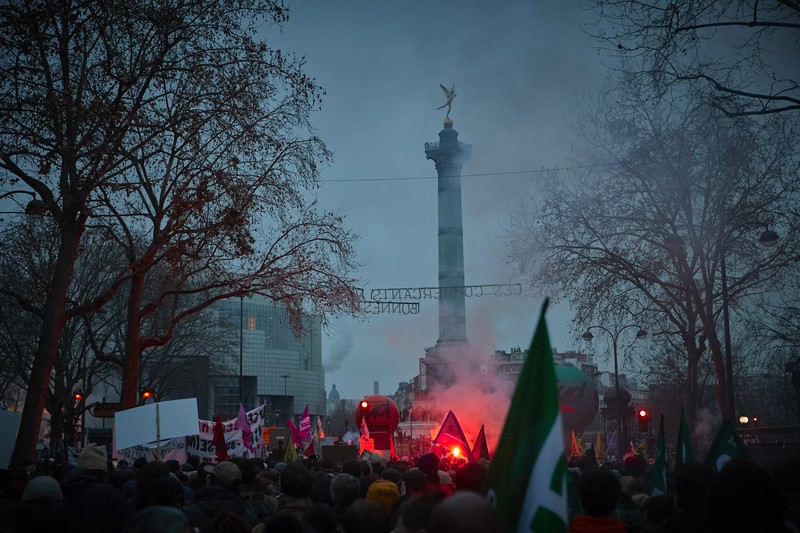 Para pengunjuk rasa berbaris melalui jalan-jalan Paris sebagai bagian dari protes dan pemogokan nasional terhadap rencana reformasi Pensiun Presiden Macron dan kenaikan biaya hidup pada 19 Januari 2023 di Paris, Prancis. Menyusul pengumuman pemerintah Prancis untuk mendorong usia pensiun dari 62 menjadi 64, serikat pekerja menyerukan aksi sosial massal dengan karyawan di bidang transportasi, pendidikan, energi, dan layanan kesehatan bergabung dengan pemogokan nasional, dengan protes besar di seluruh Prancis. Serikat CGT Prancis juga mengancam akan memutus pasokan listrik untuk anggota parlemen dan pengusaha di tengah pemogokan nasional. (Kiran Ridley/Getty Images)
