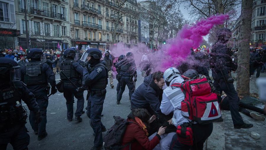 Para pengunjuk rasa berbaris melalui jalan-jalan Paris sebagai bagian dari protes dan pemogokan nasional terhadap rencana reformasi Pensiun Presiden Macron dan kenaikan biaya hidup pada 19 Januari 2023 di Paris, Prancis. Menyusul pengumuman pemerintah Prancis untuk mendorong usia pensiun dari 62 menjadi 64, serikat pekerja menyerukan aksi sosial massal dengan karyawan di bidang transportasi, pendidikan, energi, dan layanan kesehatan bergabung dengan pemogokan nasional, dengan protes besar di seluruh Prancis. Serikat CGT Prancis juga mengancam akan memutus pasokan listrik untuk anggota parlemen dan pengusaha di tengah pemogokan nasional. (Kiran Ridley/Getty Images)