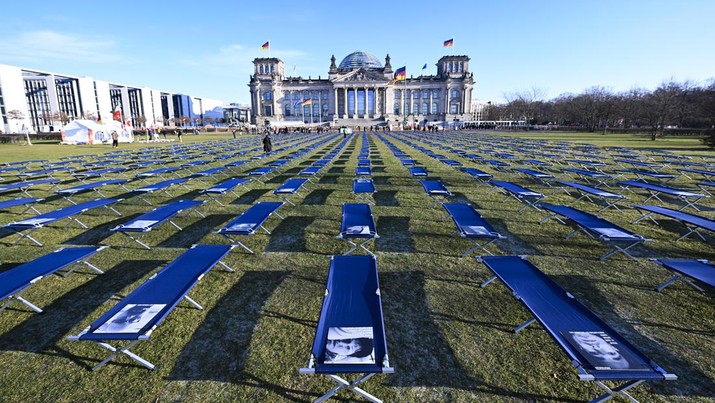 Pemandangan tempat tidur kemah dengan foto orang yang terkena dampak parah Covid-19 ditempatkan di Bundestag di Berlin pada 19 Januari 2020. Tempat tidur kemah melambangkan orang yang menderita efek kesehatan jangka panjang dari Covid-19. (Abdulhamid Hosbas/Anadolu Agency via Getty Images)