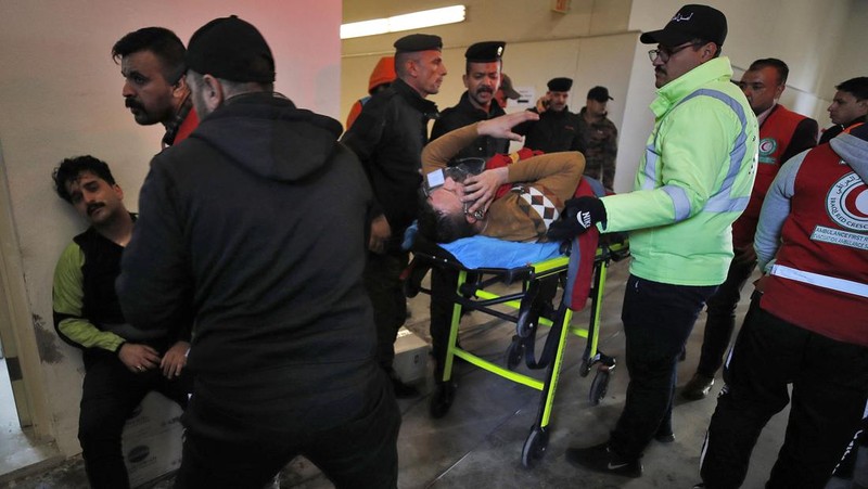 Anggota tim keamanan stadion Irak membawa seorang penggemar sepak bola yang terluka ke area darurat di Stadion Internasional Basra menyusul penyerbuan menjelang pertandingan final Piala Teluk Arab malam ini antara Irak dan Oman, pada 19 Januari 2023 di Basra. - Satu orang tewas dan puluhan lainnya terluka ketika terjadi penyerbuan di luar stadion sepak bola di Irak selatan beberapa jam sebelum final Piala Teluk, kata sumber medis dan keamanan. (HUSSEIN FALEH/AFP via Getty Images)