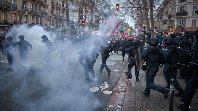 Para pengunjuk rasa berbaris melalui jalan-jalan Paris sebagai bagian dari protes dan pemogokan nasional terhadap rencana reformasi Pensiun Presiden Macron dan kenaikan biaya hidup pada 19 Januari 2023 di Paris, Prancis. Menyusul pengumuman pemerintah Prancis untuk mendorong usia pensiun dari 62 menjadi 64, serikat pekerja menyerukan aksi sosial massal dengan karyawan di bidang transportasi, pendidikan, energi, dan layanan kesehatan bergabung dengan pemogokan nasional, dengan protes besar di seluruh Prancis. Serikat CGT Prancis juga mengancam akan memutus pasokan listrik untuk anggota parlemen dan pengusaha di tengah pemogokan nasional. (Kiran Ridley/Getty Images)