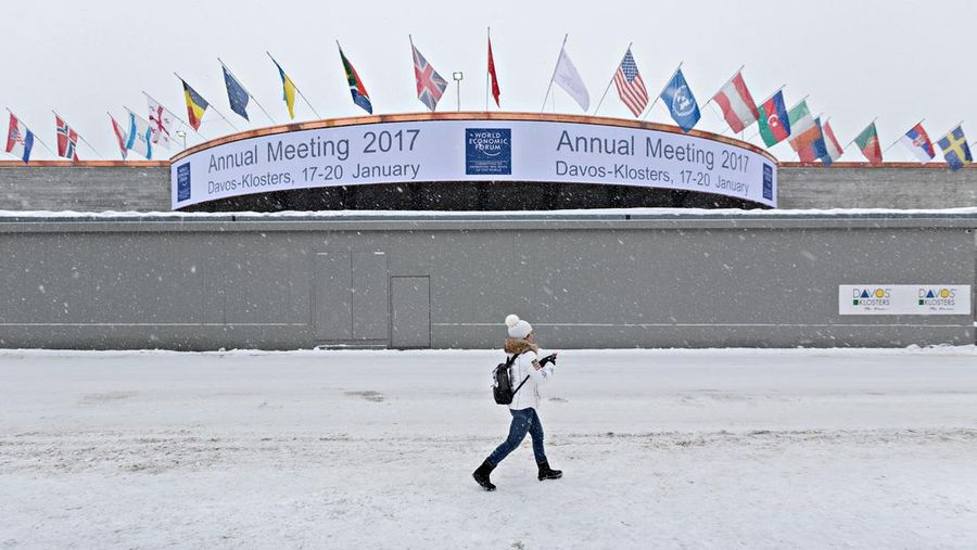 Seorang wanita menggunakan perangkat seluler saat melewati dinding keamanan yang melindungi pintu masuk ke Pusat Kongres, tempat Forum Ekonomi Dunia (WEF), di Davos, Swiss, pada Jumat, 13 Januari 2017. Pemimpin dunia, eksekutif berpengaruh, bankir dan pembuat kebijakan menghadiri pertemuan tahunan ke-47 Forum Ekonomi Dunia (WEF) di Davos dari 17-20 Januari. (Michele Limina/Bloomberg via Getty Images)
