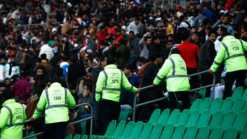 Anggota tim keamanan stadion Irak membawa seorang penggemar sepak bola yang terluka ke area darurat di Stadion Internasional Basra menyusul penyerbuan menjelang pertandingan final Piala Teluk Arab malam ini antara Irak dan Oman, pada 19 Januari 2023 di Basra. - Satu orang tewas dan puluhan lainnya terluka ketika terjadi penyerbuan di luar stadion sepak bola di Irak selatan beberapa jam sebelum final Piala Teluk, kata sumber medis dan keamanan. (HUSSEIN FALEH/AFP via Getty Images)