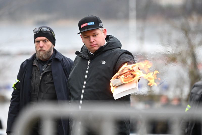 Pemimpin partai politik sayap kanan Denmark Stram Kurs Rasmus Paludan membakar salinan Alquran selama manifestasi di luar kedutaan Turki di Stockholm, Swedia, 21 Januari 2023. (Fredrik Sandberg/TT News Agency/via REUTERS)