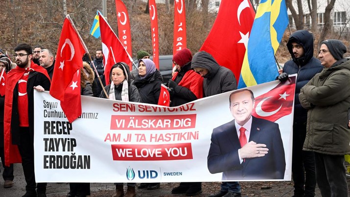 Peserta memegang bendera Turki dan spanduk bertuliskan 'Recep Tayyip Erdogan - Kami mencintaimu' selama demonstrasi organisasi pro-Turki Persatuan Demokrat Turki Eropa (UETD) untuk mendukung Turki dan Presiden Recep Tayyip Erdogan di luar Kedutaan Besar Turki di Stockholm, Swedia pada 21 Januari 2023. - Swedia membutuhkan persetujuan Turki untuk bergabung dengan NATO. Kedua negara menghentikan puluhan tahun non-blok militer tahun lalu ketika mereka mendaftar untuk bergabung dengan aliansi pertahanan Barat sebagai tanggapan atas invasi Rusia ke Ukraina. Ankara mengatakan setiap kemajuan bergantung pada langkah Swedia untuk mengekstradisi orang yang dituduhnya melakukan terorisme atau berperan dalam upaya kudeta 2016 melawan Erdogan. Turki berpendapat bahwa Swedia belum cukup berbuat untuk menindak kelompok Kurdi yang dipandang Ankara sebagai 