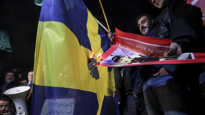 Pengunjuk rasa membakar bendera Swedia di dekat kedutaan Swedia di Amman, Yordania, Senin, 23 Januari 2023. (AP/Raad Adayleh)