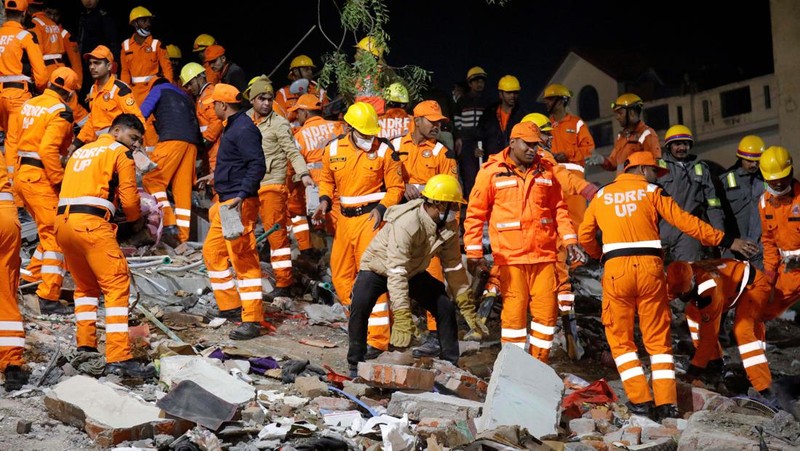 Anggota penyelamat memindahkan puing-puing setelah blok apartemen perumahan runtuh di Lucknow, India, 24 Januari 2023. (REUTERS/Pawan Kumar)