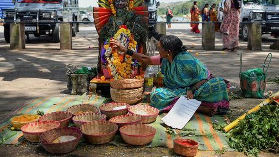 In this picture taken on September 21, 2022, a former 'devadasi' woman places a flower garland on a decorated mask of the Hindu Goddess Yellamma Devi near a pond where 'devadasis' women who were dedicated by their families to the Hindu Goddess Yellamma Devi, cleanse themselves before visiting Yellamma Devi temple in Savadatti of Belgaum district, in India's Karnataka state. - Devadasis are expected to live a life of religious devotion, forbidden from marrying other mortals, and forced at puberty to sacrifice their virginity to an older man, in return for money or gifts. (Photo by Manjunath Kiran / AFP) / TO GO WITH 'India-women-religion-rights', FOCUS by Aishwarya Kumar