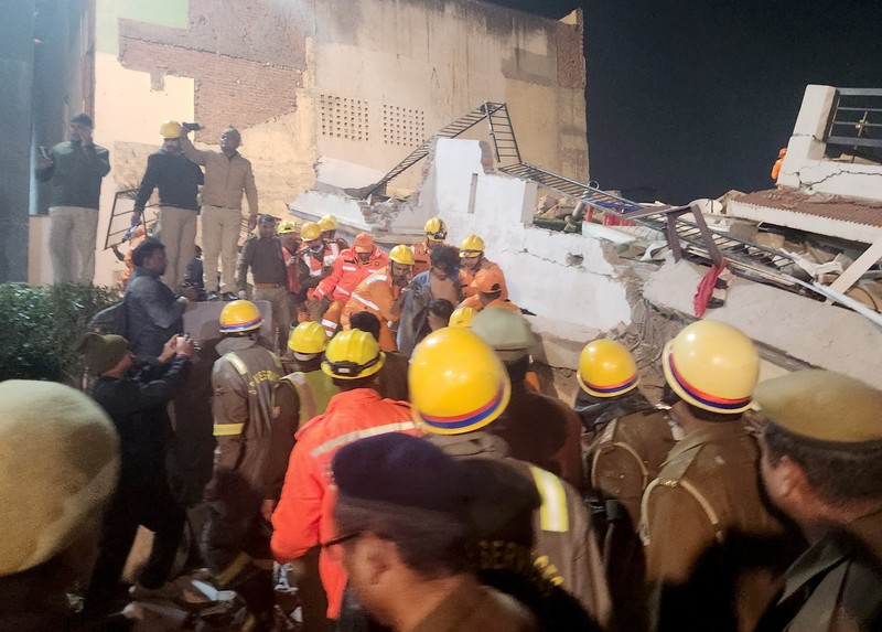 Anggota penyelamat memindahkan puing-puing setelah blok apartemen perumahan runtuh di Lucknow, India, 24 Januari 2023. (REUTERS/Pawan Kumar)