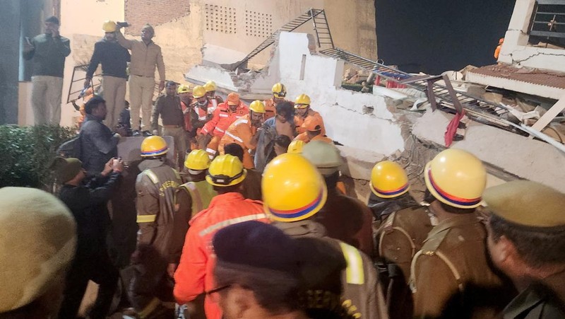 Anggota penyelamat memindahkan puing-puing setelah blok apartemen perumahan runtuh di Lucknow, India, 24 Januari 2023. (REUTERS/Pawan Kumar)