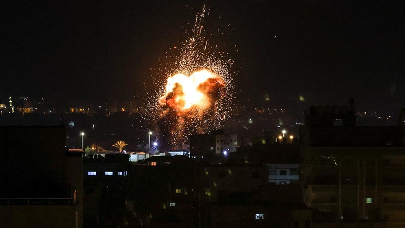Api dan asap mengepul di atas gedung-gedung di Kota Gaza saat Israel melancarkan serangan udara ke kantong Palestina pada awal 27 Januari 2023. (AFP via Getty Images/MAHMUD HAMS)