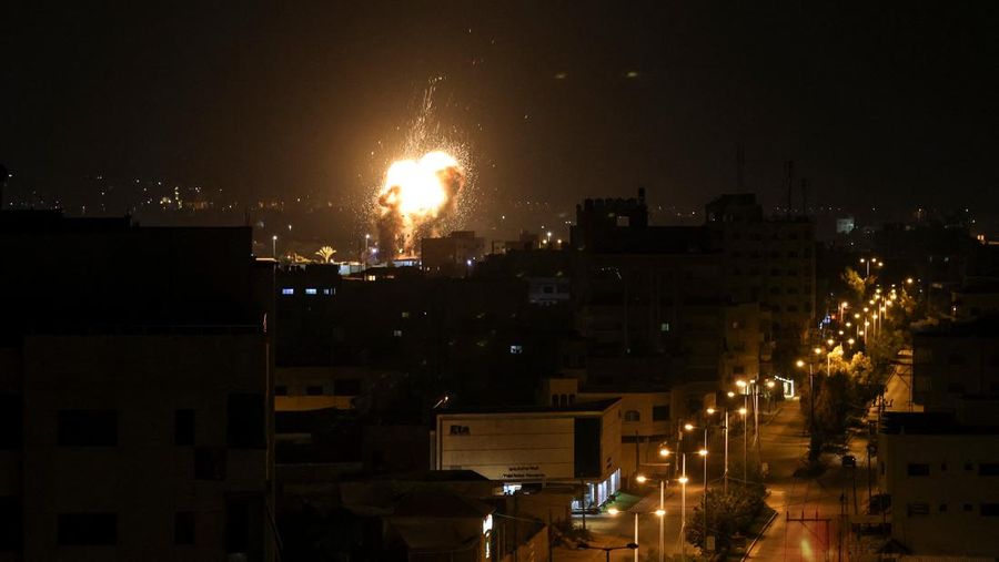 Api dan asap mengepul di atas gedung-gedung di Kota Gaza saat Israel melancarkan serangan udara ke kantong Palestina pada awal 27 Januari 2023. (AFP via Getty Images/MAHMUD HAMS)