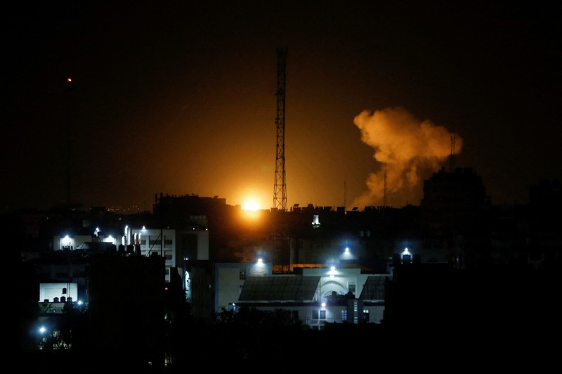 Api dan asap mengepul di atas gedung-gedung di Kota Gaza saat Israel melancarkan serangan udara ke kantong Palestina pada awal 27 Januari 2023. (AFP via Getty Images/MAHMUD HAMS)