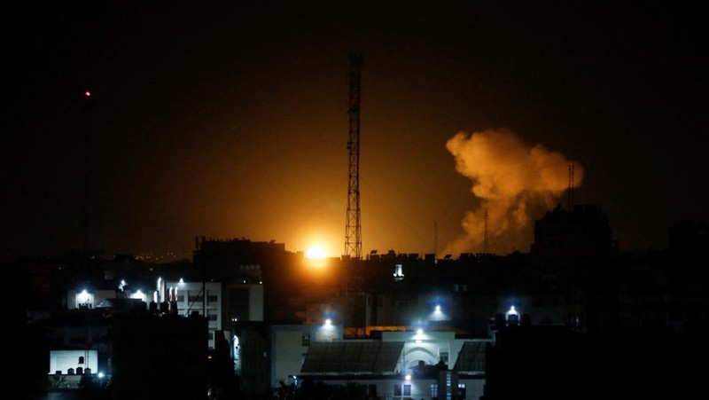 Api dan asap mengepul di atas gedung-gedung di Kota Gaza saat Israel melancarkan serangan udara ke kantong Palestina pada awal 27 Januari 2023. (AFP via Getty Images/MAHMUD HAMS)