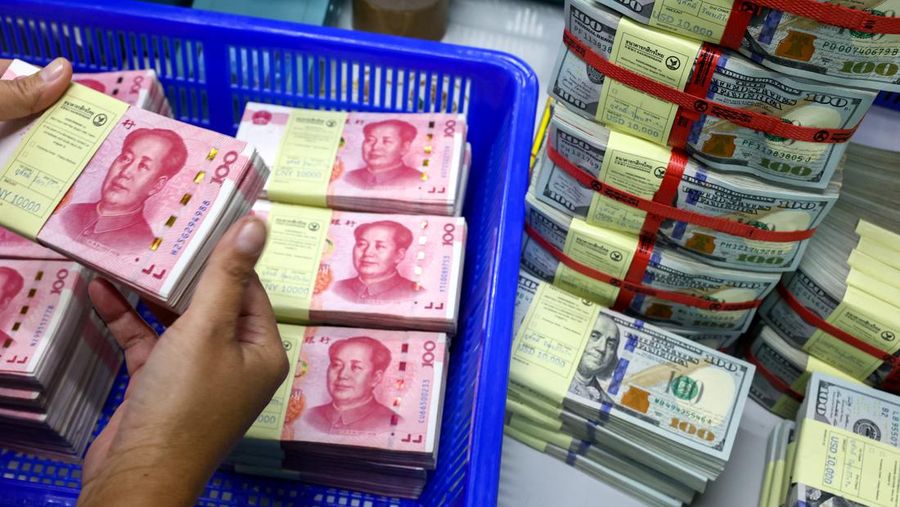 A bank employee count China’s renminbi (RMB) or yuan notes next to U.S. dollar notes at a Kasikornbank in Bangkok, Thailand, January 26, 2023. REUTERS/Athit Perawongmetha
