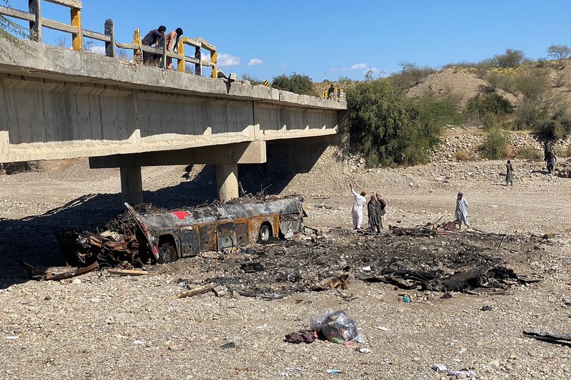 TOPSHOT - Residents look at the wreckage of a burnt passenger bus at Bela in Lasbela district of Pakistan's Balochistan province on January 29, 2023. - At least 40 people died when a bus plunged off a bridge in southwestern Pakistan and burst into flames, a government official said on January 29. (Photo by Ismail Sasoli / AFP) (Photo by ISMAIL SASOLI/AFP via Getty Images)