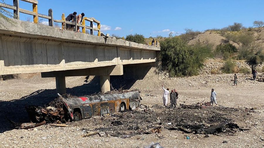 TOPSHOT - Residents look at the wreckage of a burnt passenger bus at Bela in Lasbela district of Pakistan's Balochistan province on January 29, 2023. - At least 40 people died when a bus plunged off a bridge in southwestern Pakistan and burst into flames, a government official said on January 29. (Photo by Ismail Sasoli / AFP) (Photo by ISMAIL SASOLI/AFP via Getty Images)