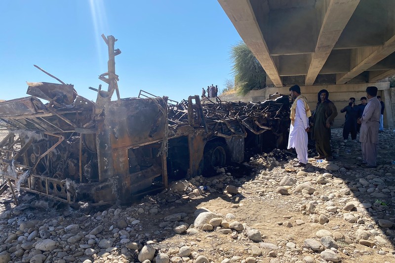 TOPSHOT - Residents look at the wreckage of a burnt passenger bus at Bela in Lasbela district of Pakistan's Balochistan province on January 29, 2023. - At least 40 people died when a bus plunged off a bridge in southwestern Pakistan and burst into flames, a government official said on January 29. (Photo by Ismail Sasoli / AFP) (Photo by ISMAIL SASOLI/AFP via Getty Images)