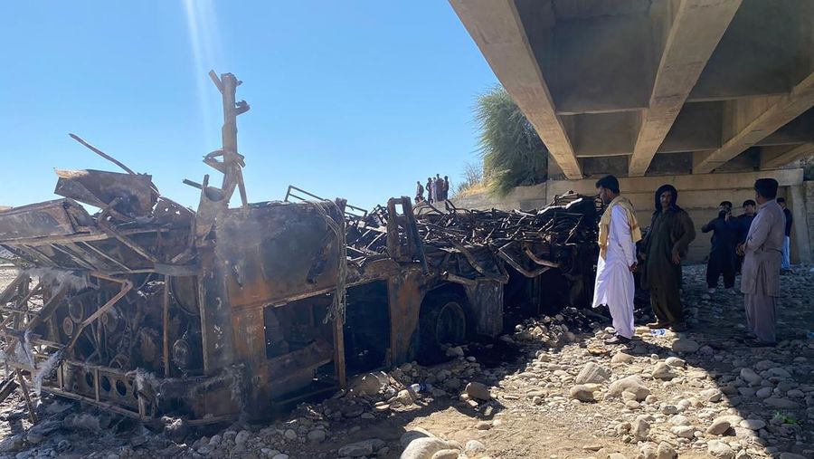 TOPSHOT - Residents look at the wreckage of a burnt passenger bus at Bela in Lasbela district of Pakistan's Balochistan province on January 29, 2023. - At least 40 people died when a bus plunged off a bridge in southwestern Pakistan and burst into flames, a government official said on January 29. (Photo by Ismail Sasoli / AFP) (Photo by ISMAIL SASOLI/AFP via Getty Images)