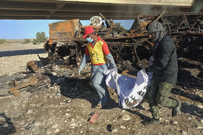 1246636430 TOPSHOT - Residents look at the wreckage of a burnt passenger bus at Bela in Lasbela district of Pakistan's Balochistan province on January 29, 2023. - At least 40 people died when a bus plunged off a bridge in southwestern Pakistan and burst into flames, a government official said on January 29. (Photo by Ismail Sasoli / AFP) (Photo by ISMAIL SASOLI/AFP via Getty Images)
