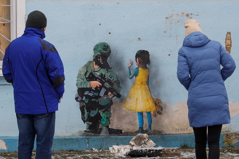 Orang-orang melihat karya seni seniman jalanan terkenal Tvboy, yang dibuat di dinding Rumah Kebudayaan, yang rusak berat selama serangan Rusia di Ukraina, di kota Irpin, di luar Kyiv, Ukraina 29 Januari 2023. Orang-orang melihat karya seni seniman jalanan terkenal Tvboy, yang dibuat di dinding Rumah Kebudayaan, yang rusak berat selama serangan Rusia di Ukraina, di kota Irpin, di luar Kyiv, Ukraina 29 Januari 2023. (REUTERS/Valentyn Ogirenko)