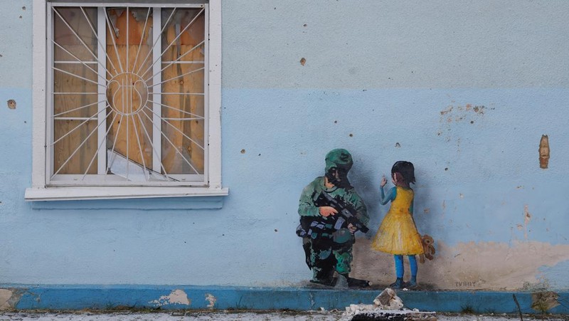 Orang-orang melihat karya seni seniman jalanan terkenal Tvboy, yang dibuat di dinding Rumah Kebudayaan, yang rusak berat selama serangan Rusia di Ukraina, di kota Irpin, di luar Kyiv, Ukraina 29 Januari 2023. (REUTERS/Valentyn Ogirenko)