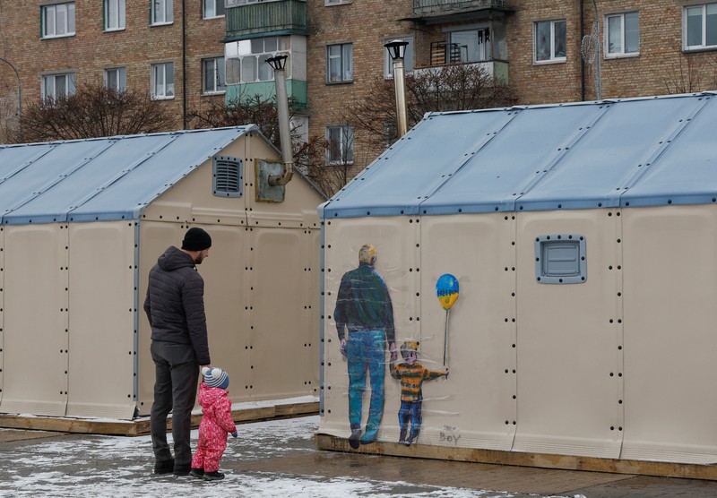 Orang-orang melihat karya seni seniman jalanan terkenal Tvboy, yang dibuat di dinding Rumah Kebudayaan, yang rusak berat selama serangan Rusia di Ukraina, di kota Irpin, di luar Kyiv, Ukraina 29 Januari 2023. (REUTERS/Valentyn Ogirenko)
