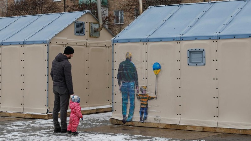 Orang-orang melihat karya seni seniman jalanan terkenal Tvboy, yang dibuat di dinding Rumah Kebudayaan, yang rusak berat selama serangan Rusia di Ukraina, di kota Irpin, di luar Kyiv, Ukraina 29 Januari 2023. (REUTERS/Valentyn Ogirenko)