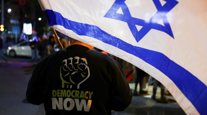 Seseorang memegang bendera Israel saat ia mengambil bagian dalam protes terhadap koalisi sayap kanan baru Perdana Menteri Benjamin Netanyahu dan usulan reformasi peradilan untuk mengurangi kekuasaan Mahkamah Agung di Tel Aviv, Israel 4 Februari 2023. (REUTERS/Ronen Zvulun)