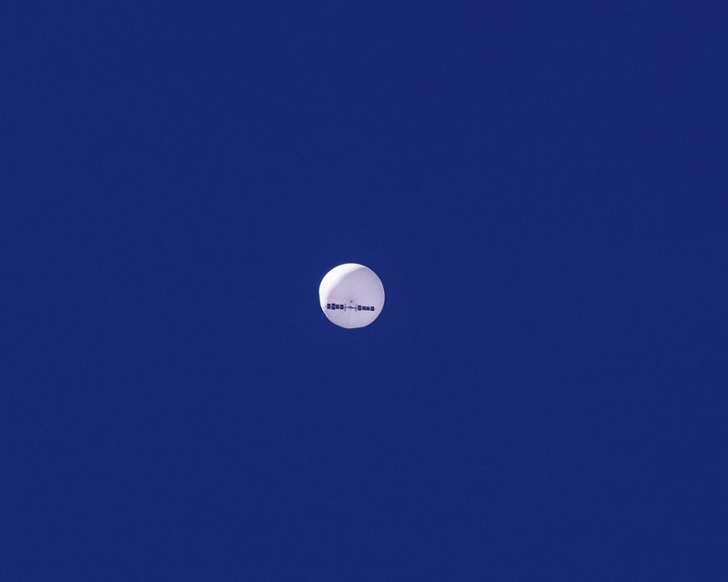 Seorang pria meneropong balon mata-mata Cina yang diduga mengapung di lepas pantai di Surfside Beach, South Carolina, AS 4 Februari 2023. (REUTERS/RANDALL HILL)