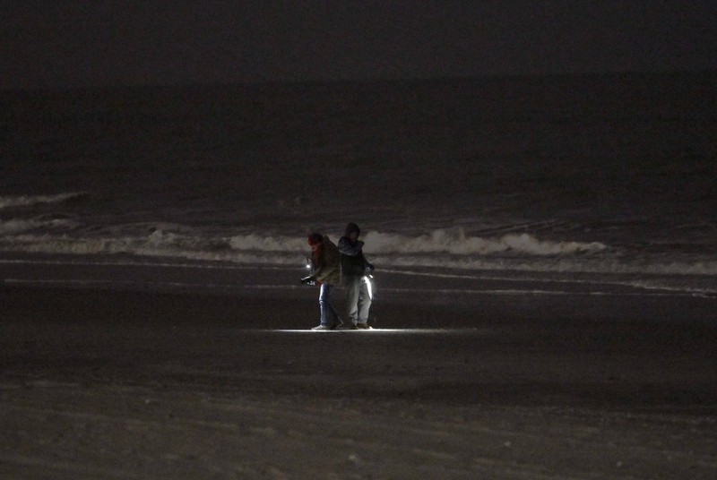 Seorang pria meneropong balon mata-mata Cina yang diduga mengapung di lepas pantai di Surfside Beach, South Carolina, AS 4 Februari 2023. (REUTERS/RANDALL HILL)