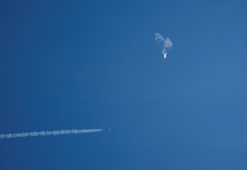 Seorang pria meneropong balon mata-mata Cina yang diduga mengapung di lepas pantai di Surfside Beach, South Carolina, AS 4 Februari 2023. (REUTERS/RANDALL HILL)
