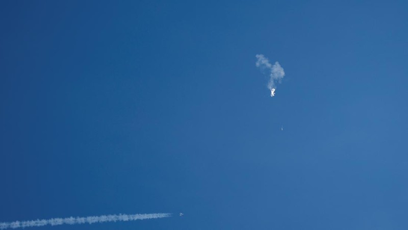 Seorang pria meneropong balon mata-mata Cina yang diduga mengapung di lepas pantai di Surfside Beach, South Carolina, AS 4 Februari 2023. (REUTERS/RANDALL HILL)