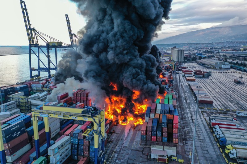 Asap mengepul dari kontainer yang terbakar di sebuah pelabuhan di kota Iskenderun yang dilanda gempa, Turki, 7 Februari 2023. (REUTERS/Benoit Tessier)