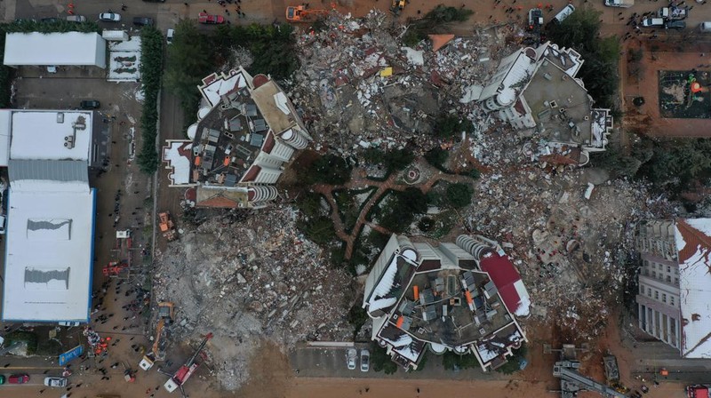 Asap mengepul dari Pelabuhan Iskenderun saat petugas penyelamat bekerja di lokasi bangunan yang runtuh pada 07 Februari 2023 di Iskenderun, Turki. Gempa berkekuatan 7,8 melanda dekat Gaziantep, Turki, pada dini hari Senin, diikuti oleh gempa berkekuatan 7,5 setelah tengah hari. Gempa tersebut menyebabkan kerusakan luas di Turki selatan dan Suriah utara dan dirasakan di negara-negara terdekat. (Burak Kara/Getty Images)
