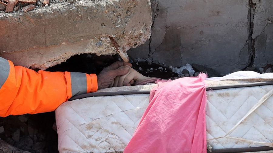 Mesut Hancer memegang tangan putrinya yang berusia 15 tahun (Irmak) yang meninggal dalam gempa bumi di Kahramanmaras, setelah gempa berkekuatan 7,8 melanda tenggara negara itu, pada (7/2/2023). (AFP/ADEM ALTAN)