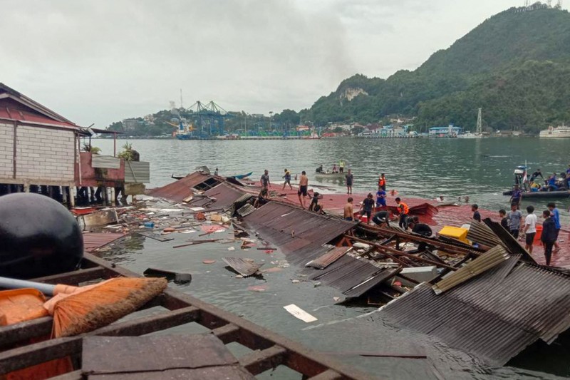 Orang-orang berdiri di atap toko yang runtuh di pelabuhan setelah gempa berkekuatan 5,1 di Jayapura, provinsi timur Indonesia Papua pada 9 Februari 2023. Orang-orang berdiri di atap toko yang runtuh di pelabuhan setelah gempa berkekuatan 5,1 di Jayapura, provinsi timur Indonesia Papua pada 9 Februari 2023. (FAISAL NARWAWAN/AFP via Getty Images)