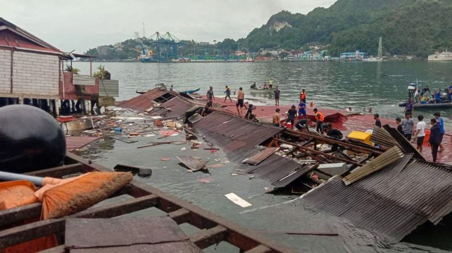 Orang-orang berdiri di atap toko yang runtuh di pelabuhan setelah gempa berkekuatan 5,1 di Jayapura, provinsi timur Indonesia Papua pada 9 Februari 2023. (FAISAL NARWAWAN/AFP via Getty Images)
