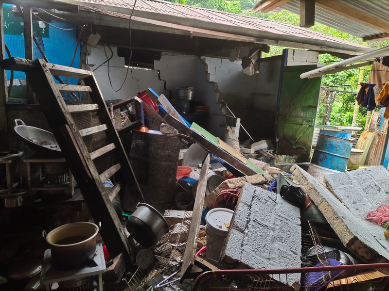 Orang-orang berdiri di atap toko yang runtuh di pelabuhan setelah gempa berkekuatan 5,1 di Jayapura, provinsi timur Indonesia Papua pada 9 Februari 2023. (FAISAL NARWAWAN/AFP via Getty Images)