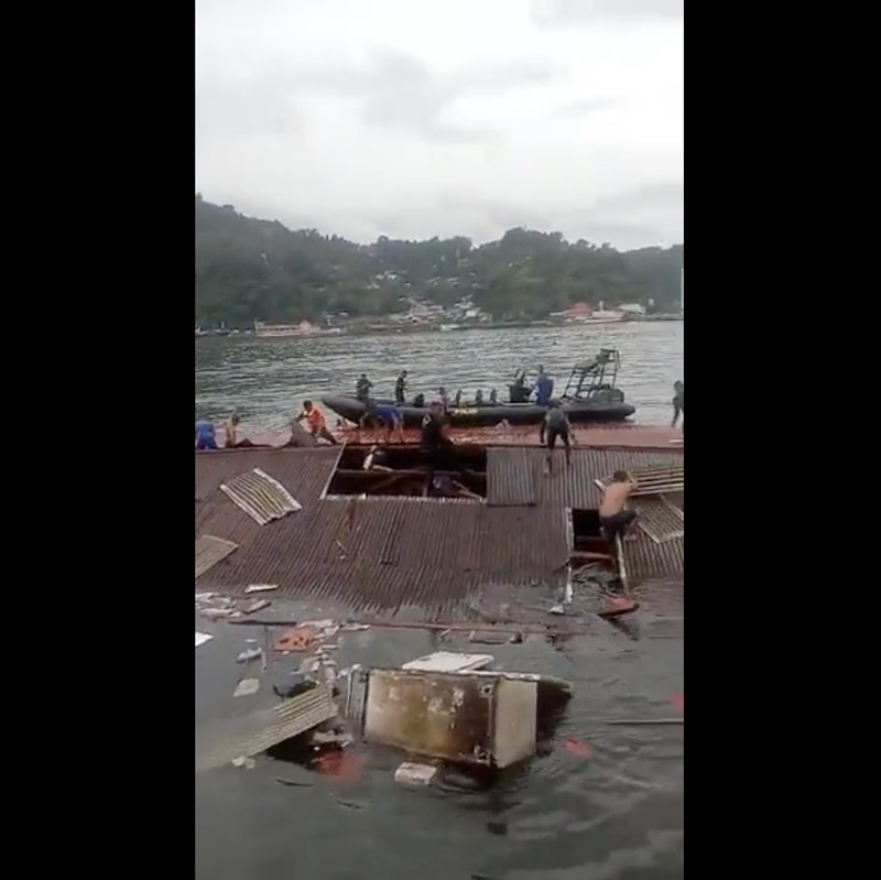 Orang-orang berdiri di atap toko yang runtuh di pelabuhan setelah gempa berkekuatan 5,1 di Jayapura, provinsi timur Indonesia Papua pada 9 Februari 2023. (FAISAL NARWAWAN/AFP via Getty Images)