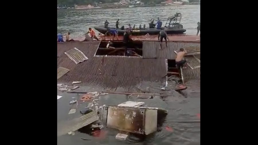 Orang-orang berdiri di atap toko yang runtuh di pelabuhan setelah gempa berkekuatan 5,1 di Jayapura, provinsi timur Indonesia Papua pada 9 Februari 2023. (FAISAL NARWAWAN/AFP via Getty Images)