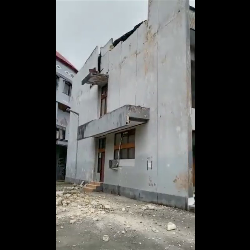 Orang-orang berdiri di atap toko yang runtuh di pelabuhan setelah gempa berkekuatan 5,1 di Jayapura, provinsi timur Indonesia Papua pada 9 Februari 2023. (FAISAL NARWAWAN/AFP via Getty Images)