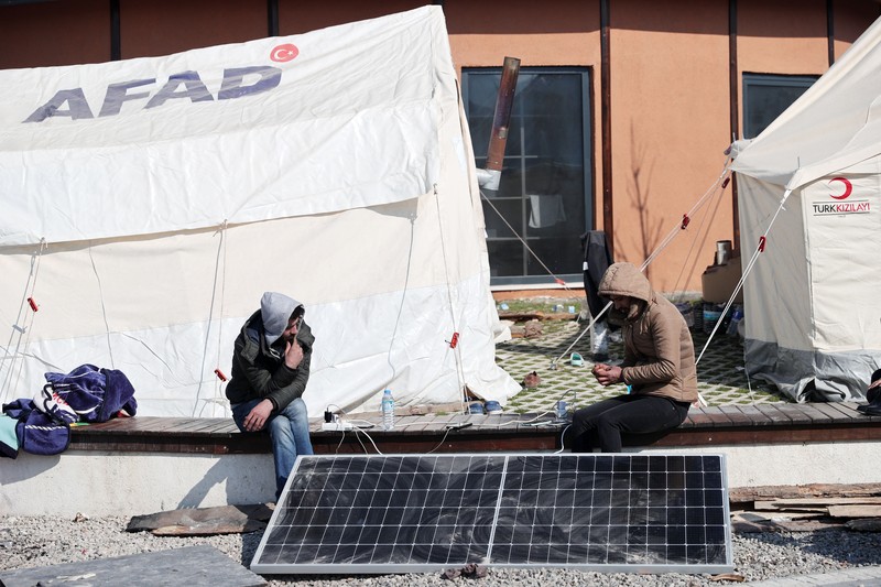 Para penyintas gempa memenuhi kebutuhan energi mendesak mereka dengan panel surya yang dipasang di kota tenda setelah gempa berkekuatan 7,7 dan 7,6 di Hatay, Turkiye pada 12 Februari 2023. Senin dini hari, gempa berkekuatan 7,7 SR, berpusat di distrik Pazarcik, mengguncang Kahramanmaras dan berguncang kuat beberapa provinsi, termasuk Gaziantep, Sanliurfa, Diyarbakir, Adana, Adiyaman, Malatya, Osmaniye, Hatay, dan Kilis. Kemudian, pada pukul 13.24. (1024GMT), gempa berkekuatan 7,6 yang berpusat di distrik Elbistan Kahramanmaras melanda wilayah tersebut. Turkiye mengumumkan 7 hari berkabung nasional setelah gempa bumi mematikan di provinsi selatan. (Oguz Yeter/Anadolu Agency via Getty Images)
