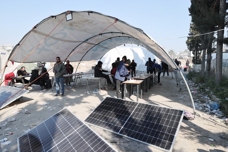 Para penyintas gempa memenuhi kebutuhan energi mendesak mereka dengan panel surya yang dipasang di kota tenda setelah gempa berkekuatan 7,7 dan 7,6 di Hatay, Turkiye pada 12 Februari 2023. Senin dini hari, gempa berkekuatan 7,7 SR, berpusat di distrik Pazarcik, mengguncang Kahramanmaras dan berguncang kuat beberapa provinsi, termasuk Gaziantep, Sanliurfa, Diyarbakir, Adana, Adiyaman, Malatya, Osmaniye, Hatay, dan Kilis. Kemudian, pada pukul 13.24. (1024GMT), gempa berkekuatan 7,6 yang berpusat di distrik Elbistan Kahramanmaras melanda wilayah tersebut. Turkiye mengumumkan 7 hari berkabung nasional setelah gempa bumi mematikan di provinsi selatan. (Oguz Yeter/Anadolu Agency via Getty Images)