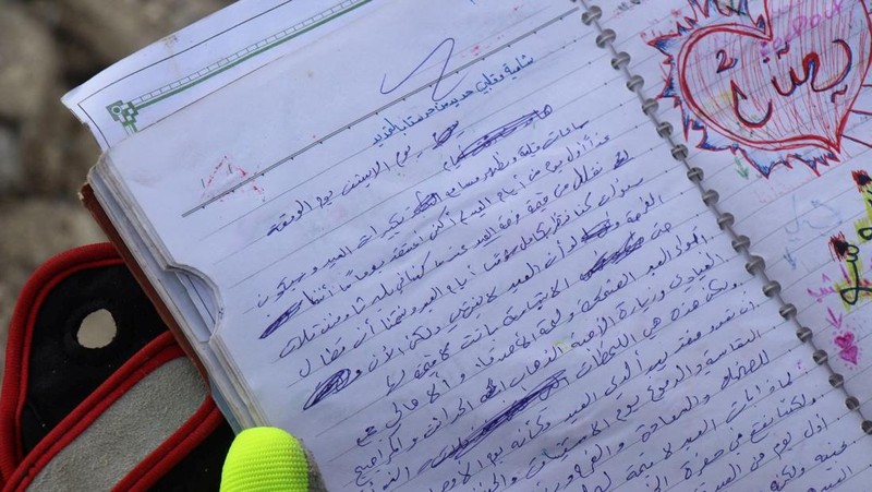 Seorang anggota White Helmets melihat buku catatan yang ditemukan di sebuah bangunan yang rusak, setelah gempa bumi, di kota Jandaris yang dikuasai pemberontak, Suriah, 10 Februari 2023. (White Helmets/Handout via REUTERS)