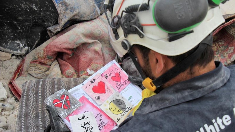Seorang anggota White Helmets melihat buku catatan yang ditemukan di sebuah bangunan yang rusak, setelah gempa bumi, di kota Jandaris yang dikuasai pemberontak, Suriah, 10 Februari 2023. (White Helmets/Handout via REUTERS)